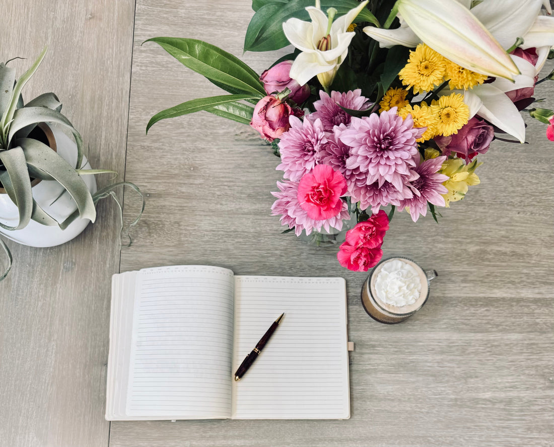 open journal on table with coffee and flowers
