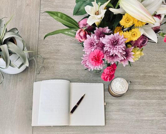 open journal on table with coffee and flowers